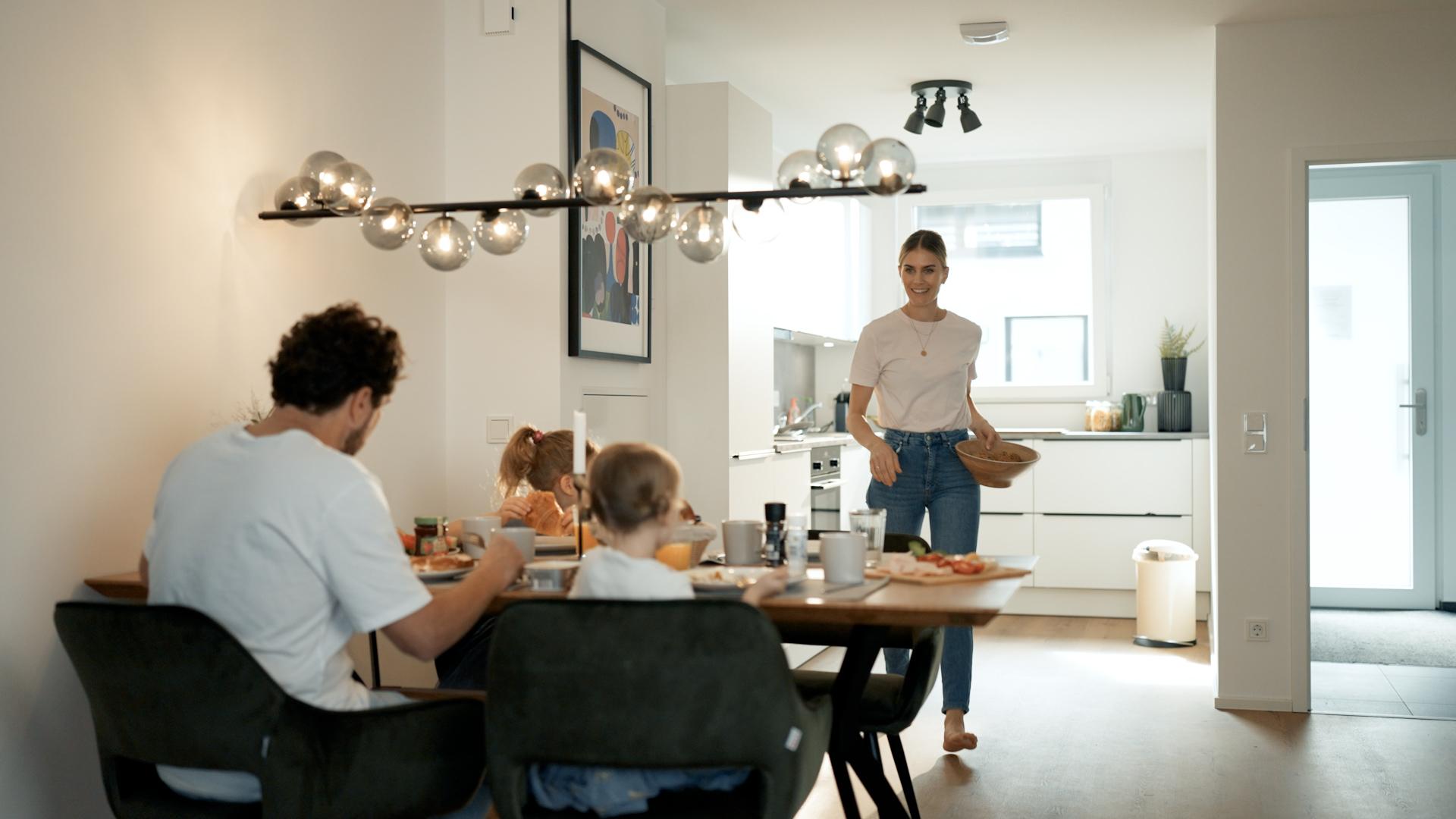 Familie beim Frühstück im Essbereich mit moderner Küche in einer Movida-Immobilie zur Miete.