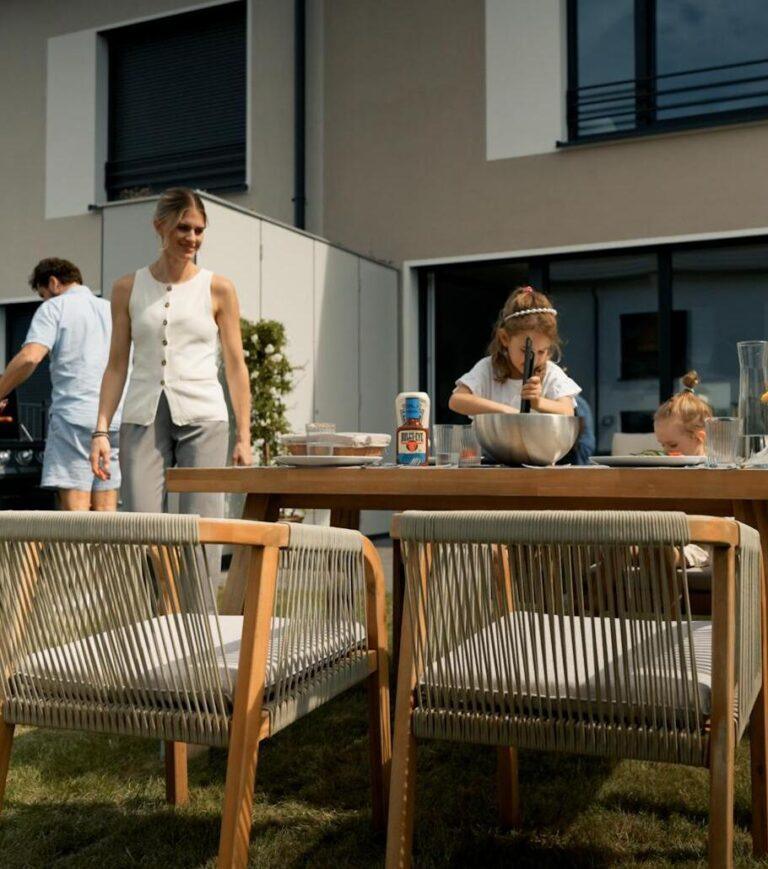 Familie beim Grillen und gemeinsamen Essen im Garten mit Terrasse einer Movida-Immobilie zur Miete.