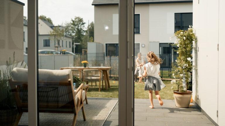 Movida Familie im Garten mit Blick von der Terrasse ins Haus