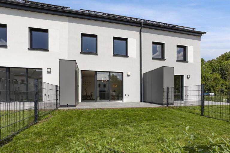 Movida Haus Neubau mit Terrasse, Garten und großen Fenstern bei Sonnenschein zur Miete