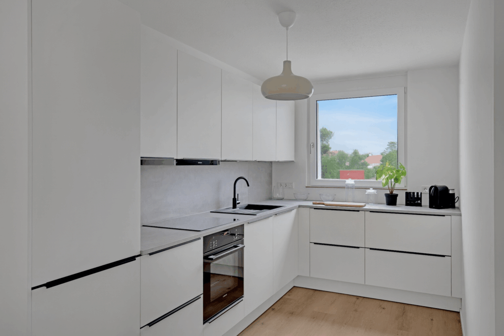 Moderne Movida Küche in Weiß mit Einbaugeräten, Holzfußboden und Fensterblick