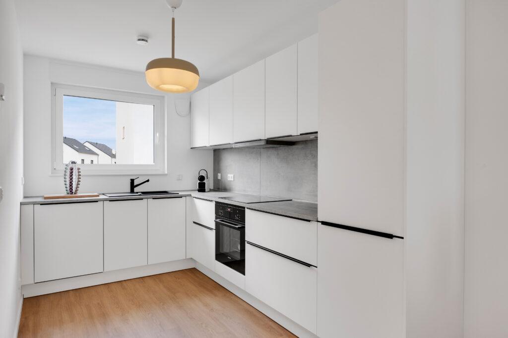 Movida Neubau mit moderner weißer Einbauküche in L-Form und grauer Arbeitsplatte zur Miete
