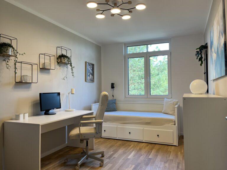 Modernes Schlafzimmer im MoVida Haus mit integriertem Arbeitsbereich, Schreibtisch und großem Fenster mit Gartenblick