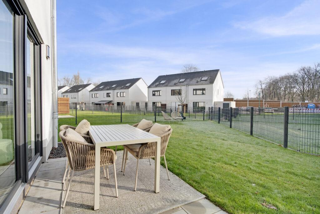 Terrasse mit Sitzgruppe und Blick auf moderne Wohnhäuser von MoVida – Sustainable Living