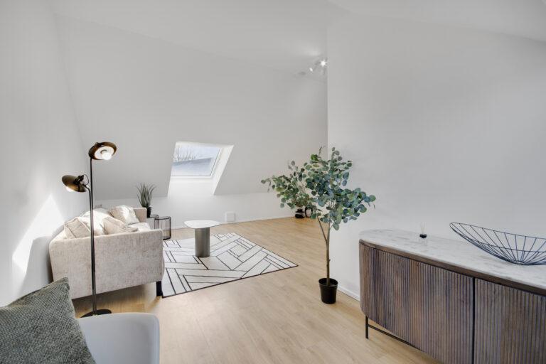 Heller Aufenthaltsraum im Dachgeschoss eines Reihenhauses mit Sitzbereich, Dachfenster und Holzfußboden.