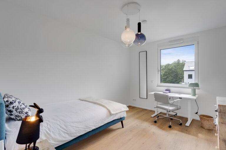 Movida Neubau Schlafzimmer mit Einzelbett, Schreibtisch und großem Fensterblick ins Grüne