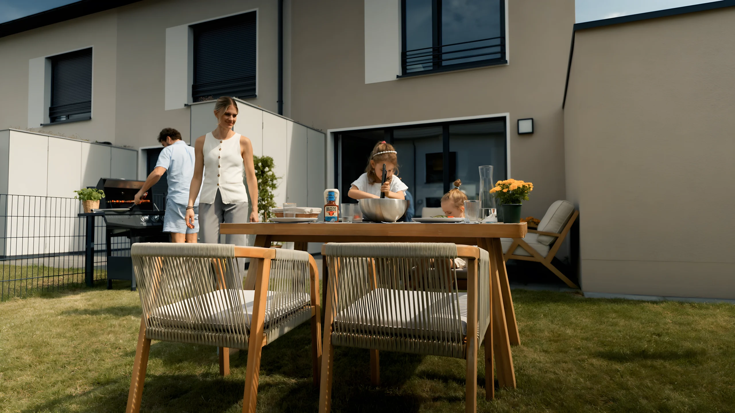 Familie beim Grillen und gemeinsamen Essen im Garten mit Terrasse einer Movida-Immobilie zur Miete.